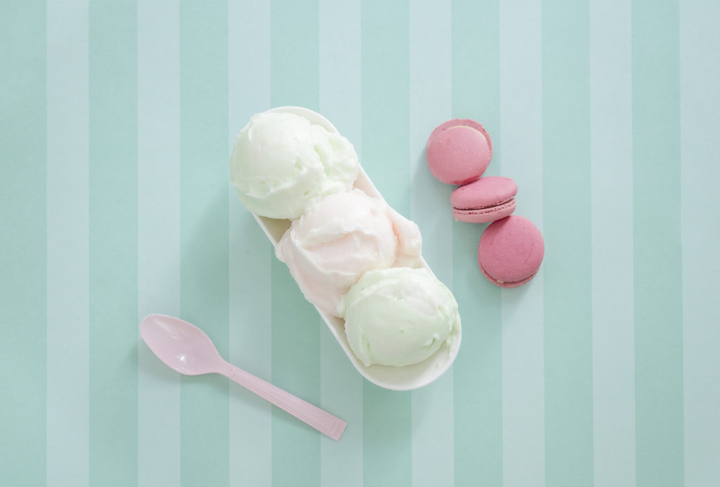 drie bolletjes ijs in een bakje met roze macarons en een lepel