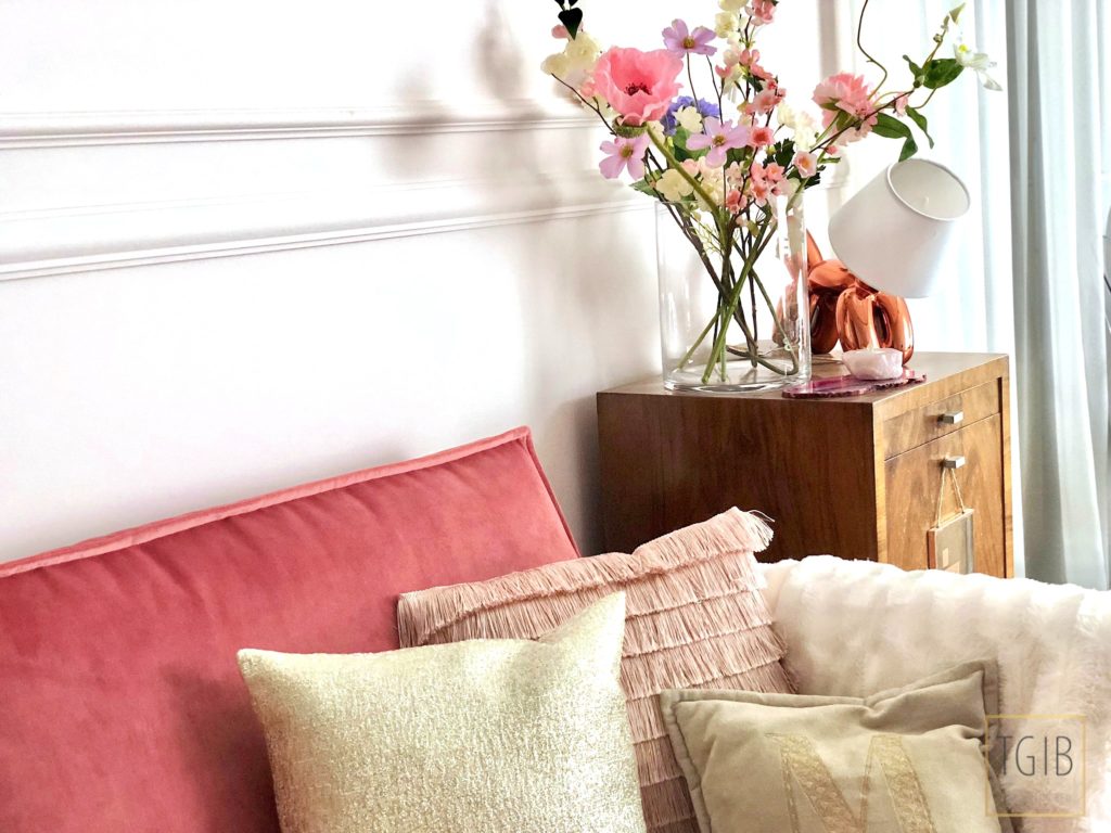 roze bank met kussens en bloemen in woonkamer